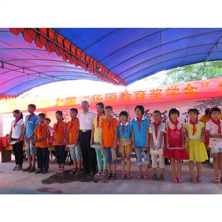 2015年6月18日，组织全体会员企业代表赴湛江雷州题桥小学颁发“华国教育奖学金”，图为周会长与获得奖学金的学生们合照。